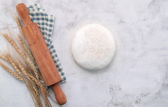 Wheat ears and wheat grains setup with rolling pin on white concrete background.