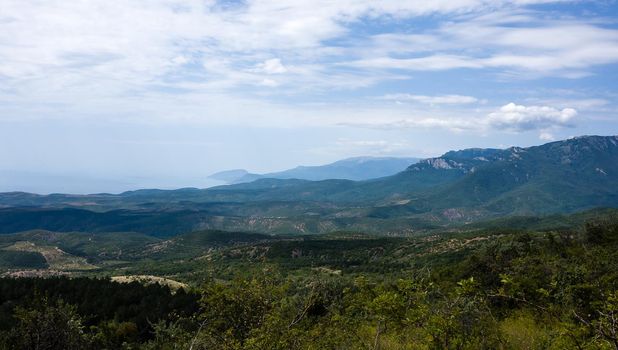 View of the mountains covered with green forest, descending to the right to the sea.