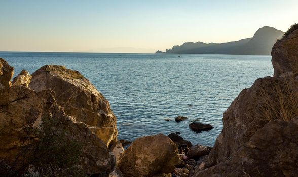 Rocks, slight sea waves at sunset on a warm summer evening.