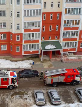 Fire engine in the courtyard of a multi-storey residential building in winter.