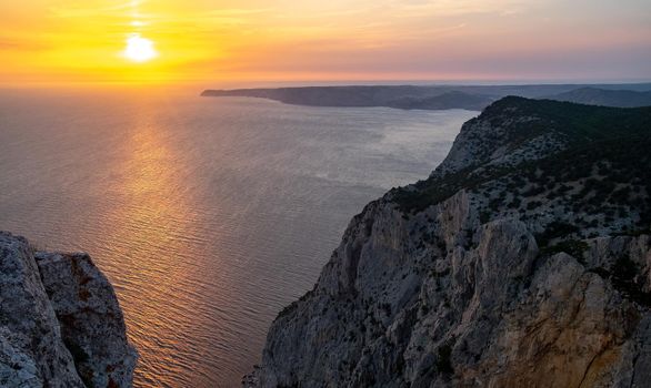 The sun setting into the sea and the long cape crashing into the Black Sea at sunset. Coast of the Crimean Peninsula near Balaklava.