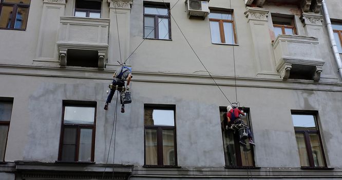 Industrial climbers plaster the wall of a building in Moscow.