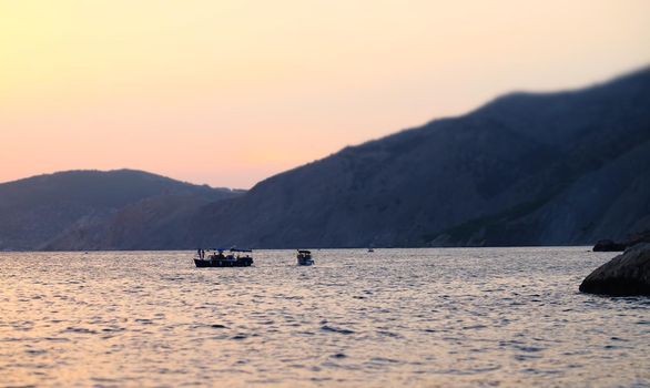 A pleasure boat in a quiet bay of the Black Sea in the light of the setting sun.