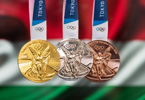 April 25, 2021 Tokyo, Japan. Gold, silver and bronze medals of the XXXII Summer Olympic Games 2020 in Tokyo on the background of the flag of Hungary.