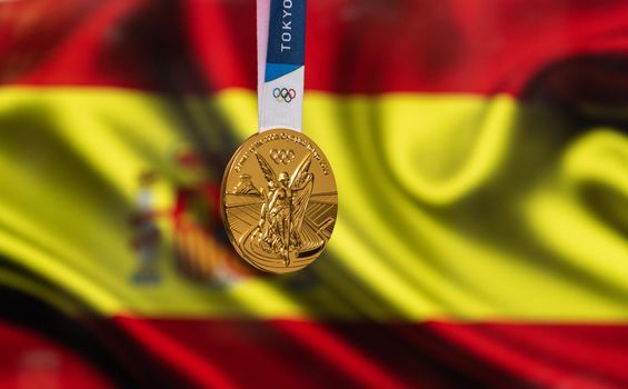 April 25, 2021 Tokyo, Japan. Gold medal of the XXXII Summer Olympic Games 2020 in Tokyo on the background of the flag of Spain.