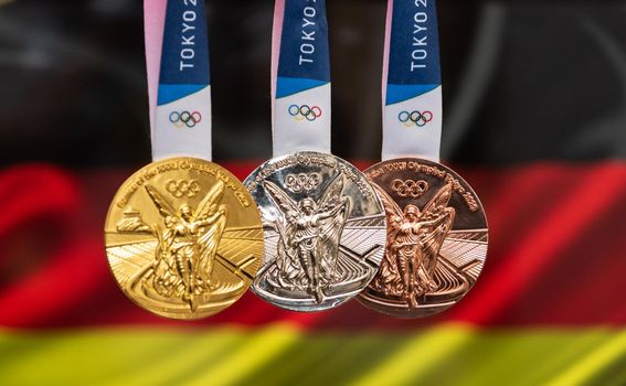 April 25, 2021 Tokyo, Japan. Gold, silver and bronze medals of the XXXII Summer Olympic Games 2020 in Tokyo on the background of the flag of Germany.