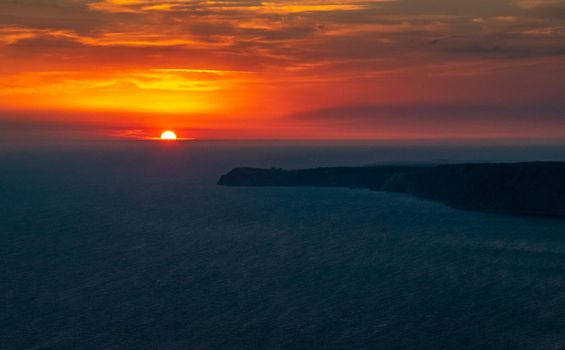 The sun setting into the sea and the long cape crashing into the Black Sea at sunset. Coast of the Crimean Peninsula near Balaklava.