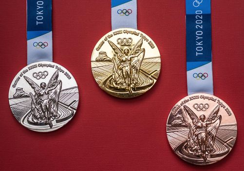 April 25, 2021 Tokyo, Japan. Gold, silver and bronze medals of the XXXII Summer Olympic Games in Tokyo on a red background.