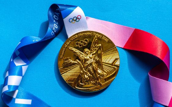 April 25, 2021 Tokyo, Japan. Gold medal of the XXXII Summer Olympic Games in Tokyo on a blue background.