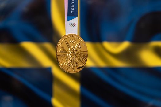April 25, 2021 Tokyo, Japan. Gold medal of the XXXII Summer Olympic Games 2020 in Tokyo on the background of the flag of Sweden.
