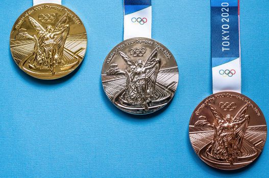 April 25, 2021 Tokyo, Japan. Gold, silver and bronze medals of the XXXII Summer Olympic Games in Tokyo on a blue background.
