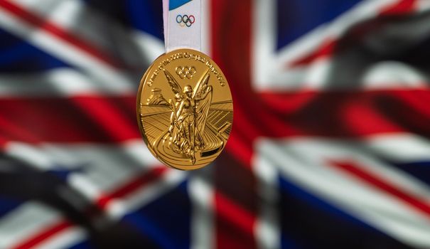 April 25, 2021 Tokyo, Japan. Gold medal of the XXXII Summer Olympic Games 2020 in Tokyo on the background of the flag of Great Britain.