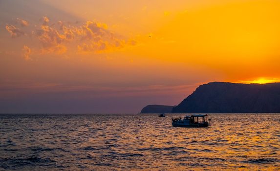 A pleasure boat in a quiet bay of the Black Sea in the light of the setting sun.