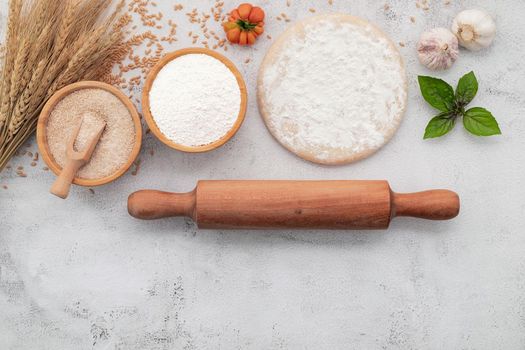 The ingredients for homemade pizza dough with wheat ears ,wheat flour and wheat grains set up on white concrete background.