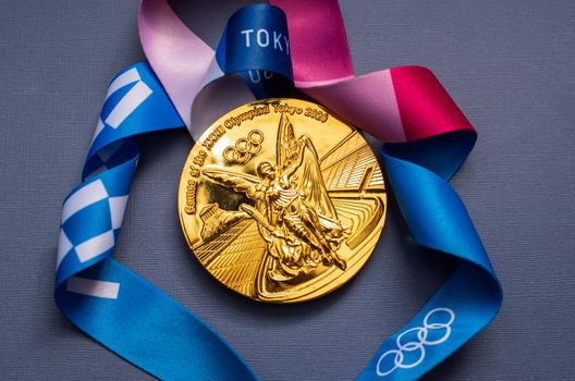 April 25, 2021 Tokyo, Japan. Gold medal of the XXXII Summer Olympic Games in Tokyo on a blue background.