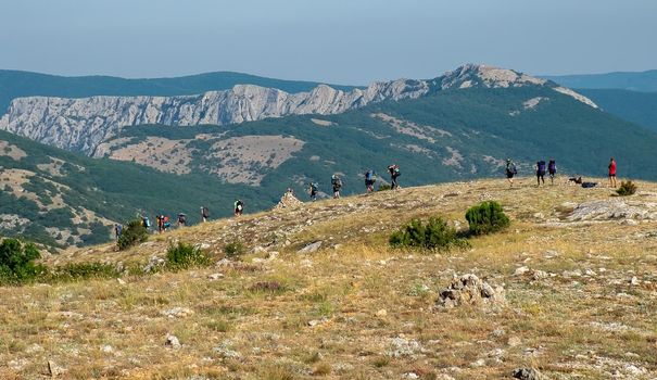 A group of tourists is walking along a trail in the mountains of the Crimean peninsula.