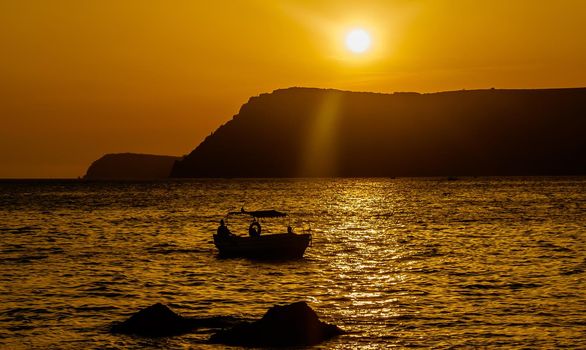 A pleasure boat in a quiet bay of the Black Sea in the light of the setting sun.