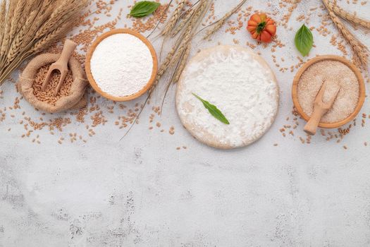 The ingredients for homemade pizza dough with wheat ears ,wheat flour and wheat grains set up on white concrete background.