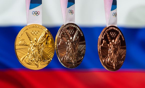 April 25, 2021 Tokyo, Japan. Gold, silver and bronze medals of the XXXII Summer Olympic Games 2020 in Tokyo on the background of the flag of Russia.