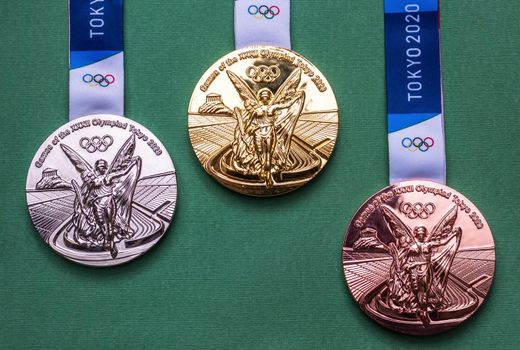 April 25, 2021 Tokyo, Japan. Gold, silver and bronze medals of the XXXII Summer Olympic Games in Tokyo on a green background.
