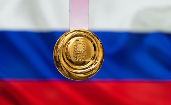 April 25, 2021 Tokyo, Japan. Gold medal of the XXXII Summer Olympic Games 2020 in Tokyo on the background of the flag of Russia.