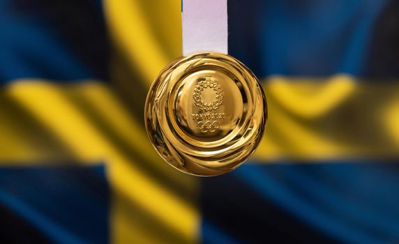 April 25, 2021 Tokyo, Japan. Gold medal of the XXXII Summer Olympic Games 2020 in Tokyo on the background of the flag of Sweden.