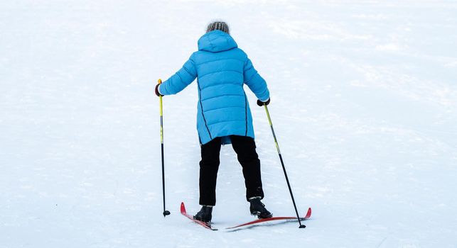 A woman in a blue jacket skiing up a snowy slope.