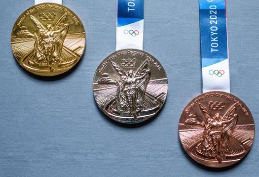 April 25, 2021 Tokyo, Japan. Gold, silver and bronze medals of the XXXII Summer Olympic Games in Tokyo on a dark blue background.