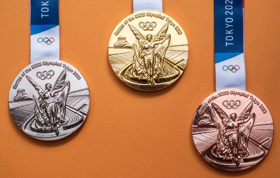 April 25, 2021 Tokyo, Japan. Gold, silver and bronze medals of the XXXII Summer Olympic Games in Tokyo on a yellow background.