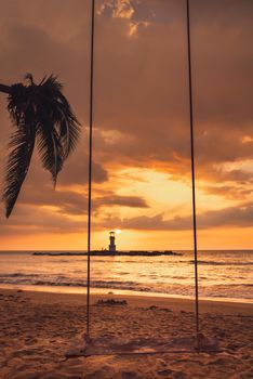 Seascape Scenery View With Empty Swing During Dramatic Cloudy at Sunset, Nature Landscape Tropical Seashore Scenic and Beautiful Beach Against Lighthouse and Horizon Over Background. Relax Vacation
