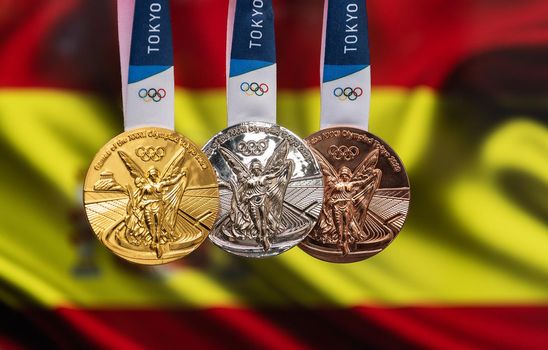 April 25, 2021 Tokyo, Japan. Gold, silver and bronze medals of the XXXII Summer Olympic Games 2020 in Tokyo on the background of the flag of Spain.