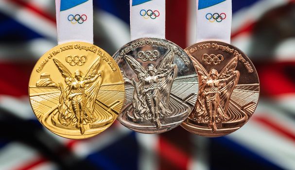 April 25, 2021 Tokyo, Japan. Gold, silver and bronze medals of the XXXII Summer Olympic Games 2020 in Tokyo on the background of the flag of Great Britain.