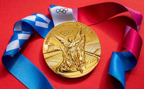 April 25, 2021 Tokyo, Japan. Gold medal of the XXXII Summer Olympic Games in Tokyo on a red background.