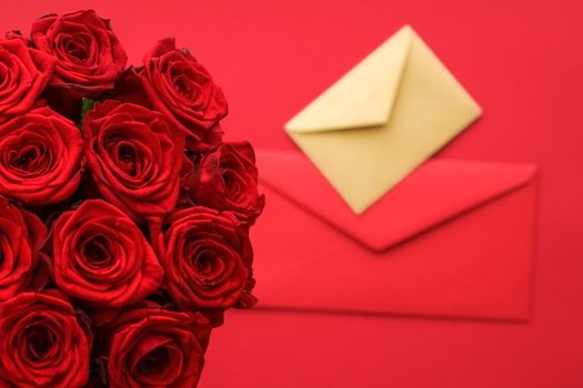 Holiday gift, flowers flatlay and happy relationship concept - Love letter and flower delivery service on Valentines Day, luxury bouquet of red roses and card envelopes on red background