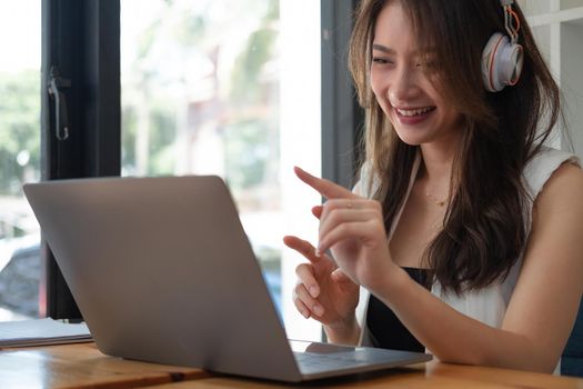 Shot of Happy young asian business woman wears headset talk to online video conference call on laptop computer with her business team during quarantine covid-19 self isolation at home,VDO Call Conference Concept