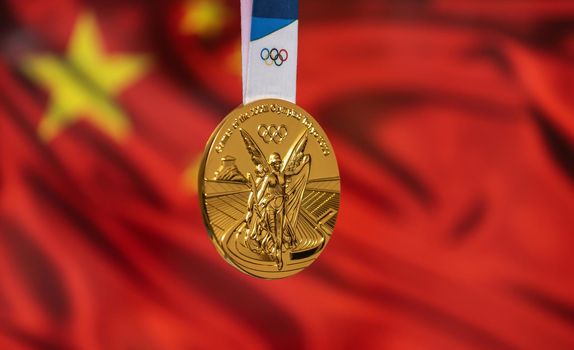 April 25, 2021 Tokyo, Japan. Gold medal of the XXXII Summer Olympic Games 2020 in Tokyo on the background of the flag of China.