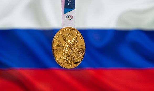 April 25, 2021 Tokyo, Japan. Gold medal of the XXXII Summer Olympic Games 2020 in Tokyo on the background of the flag of Russia.
