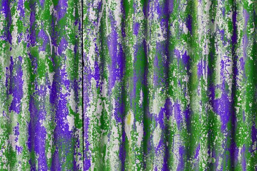 colorful motley peeled off green and purple paint layers on corrugated zinc coated steel sheet - full frame background and texture