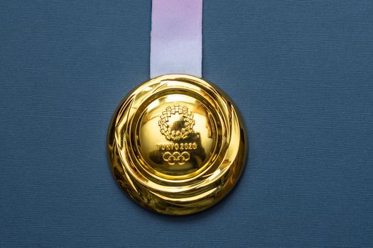 April 25, 2021 Tokyo, Japan. Gold medal of the XXXII Summer Olympic Games in Tokyo on a blue background.