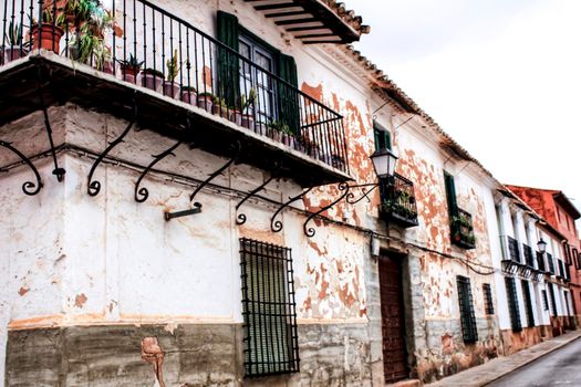 Old white facades, balconies and vintage lanterns in a street of Villanueva de los Infantes, Ciudad Real, Spain