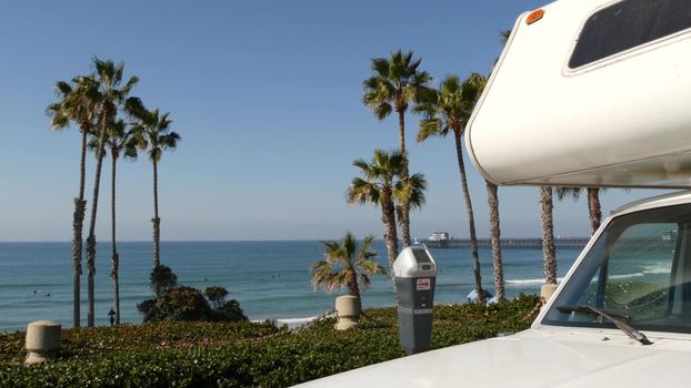 Motorhome trailer or caravan for road trip. Waterfront tropical palm trees and pacific ocean beach, Oceanside California USA. Beachfront vacations in camper van, RV motor home. Mobile home campervan.