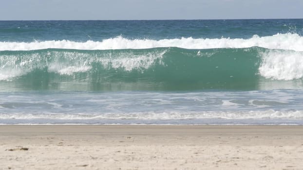 Pacific ocean big waves splashing, California coast USA. Water surface texture and sea foam. Seascape near sandy beach, blue water. Low angle view of turquoise tide. Sunny tropical windy summer day.