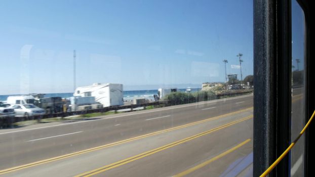 View from bus window, pacific coast highway 1, freeway 101 historic route, California USA. Road trip in public passenger transport. Journey along summer ocean or sea near Los Angeles. Yellow cord.