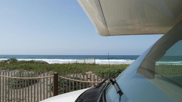 Motorhome trailer, caravan for road trip. Waterfront Encinitas, waves of pacific ocean sea beach, California coast USA. Beachfront vacations, camper van RV motor home. Mobile home campervan. Blue sky.