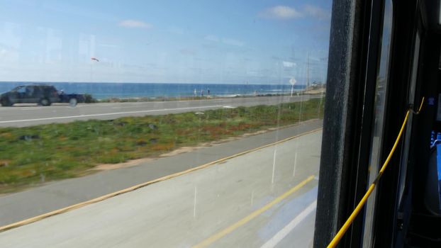 View from bus window, pacific coast highway 1, freeway 101 historic route, California USA. Road trip in public passenger transport. Journey along summer ocean or sea near Los Angeles. Yellow cord.