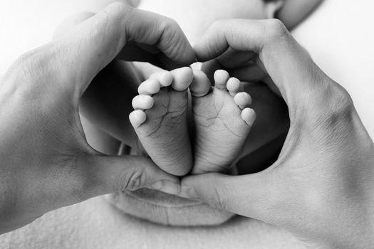 Feet of a newborn in the hands of a father, parent. Studio photography, black and white. Happy family concept. High quality photo