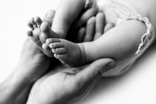 Feet of a newborn in the hands of a father, parent. Studio photography, black and white. Happy family concept. High quality photo