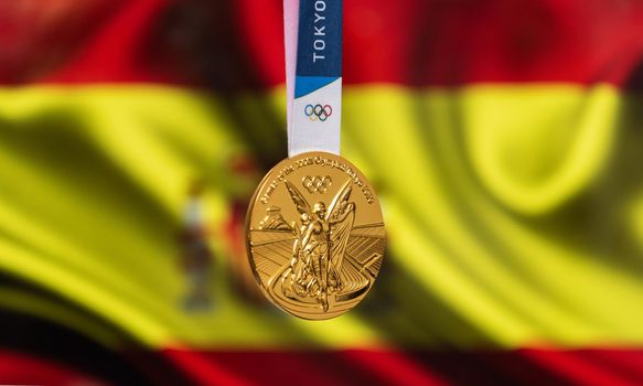 April 25, 2021 Tokyo, Japan. Gold medal of the XXXII Summer Olympic Games 2020 in Tokyo on the background of the flag of Spain.