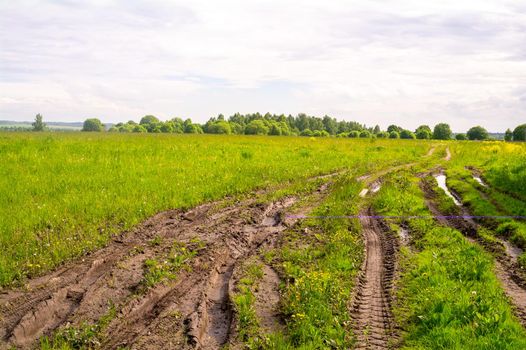 Blurred muddy road track after rain in the field, summer