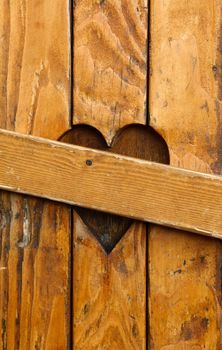 Close up closed wooden window shutters with one heart shape as symbol of divorce, broken heart and love problems